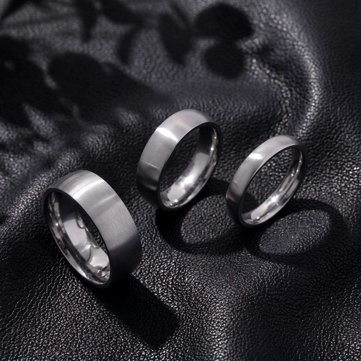 VLKRY - Pure Titanium Jewelry Ring-Set mit gebürstetem mattem Finish auf schwarzem Lederhintergrund
