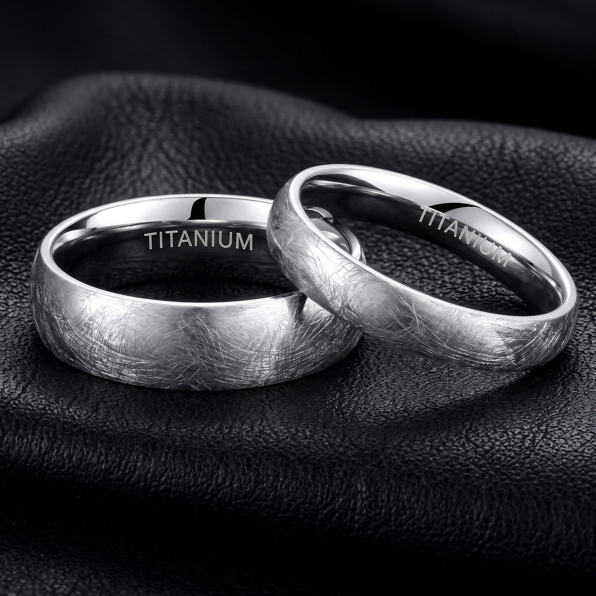 Zwei VLKRY - Pure Titanium Jewelry Frost Ringe mit strukturierter, eisgebürsteter Oberfläche auf schwarzem Leder.