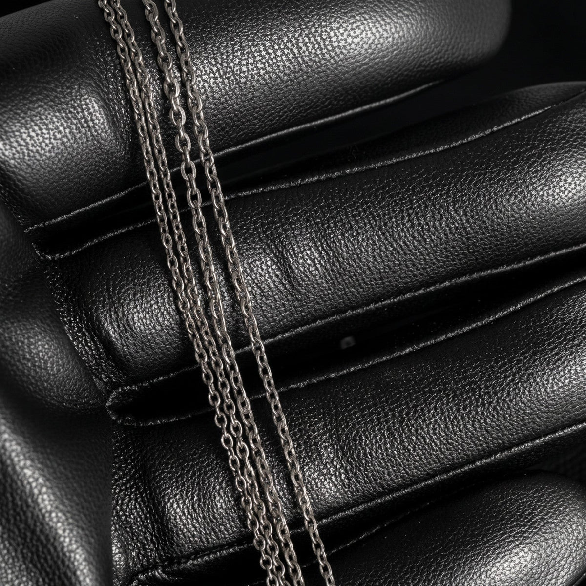 VLKRY - Pure Titanium Jewelry Thread Halskette aus feinen, grauen Titangliedern auf einem schwarzen Lederhandschuh