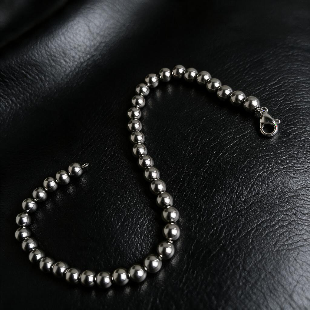 VLKRY - Pure Titanium Jewelry Pearl Armband aus silberfarbenen, 5mm runden Titanperlen auf schwarzem Lederhintergrund.